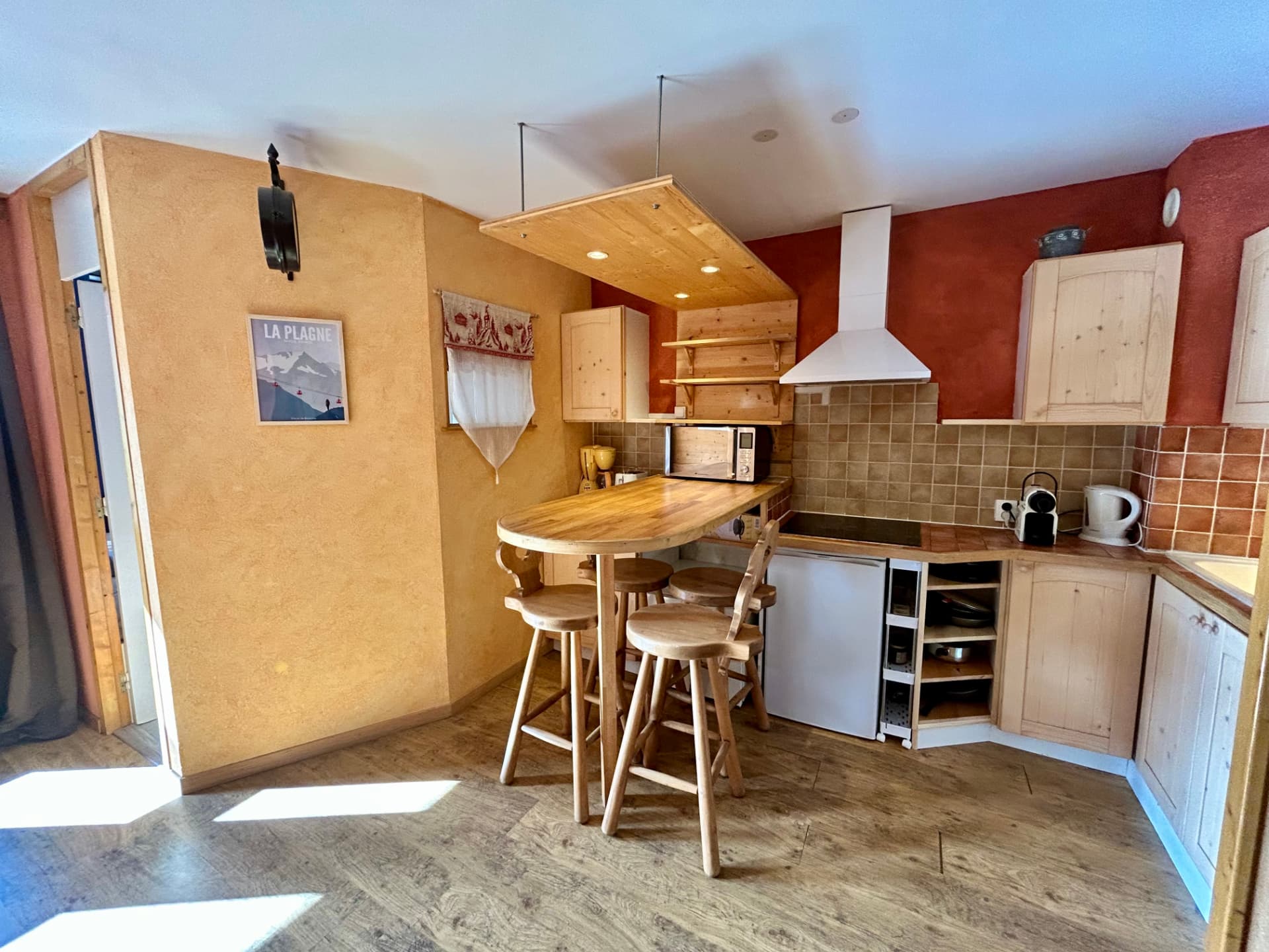 Cuisine ouverte avec bar en bois, tabourets et plaque vitrocéramique
