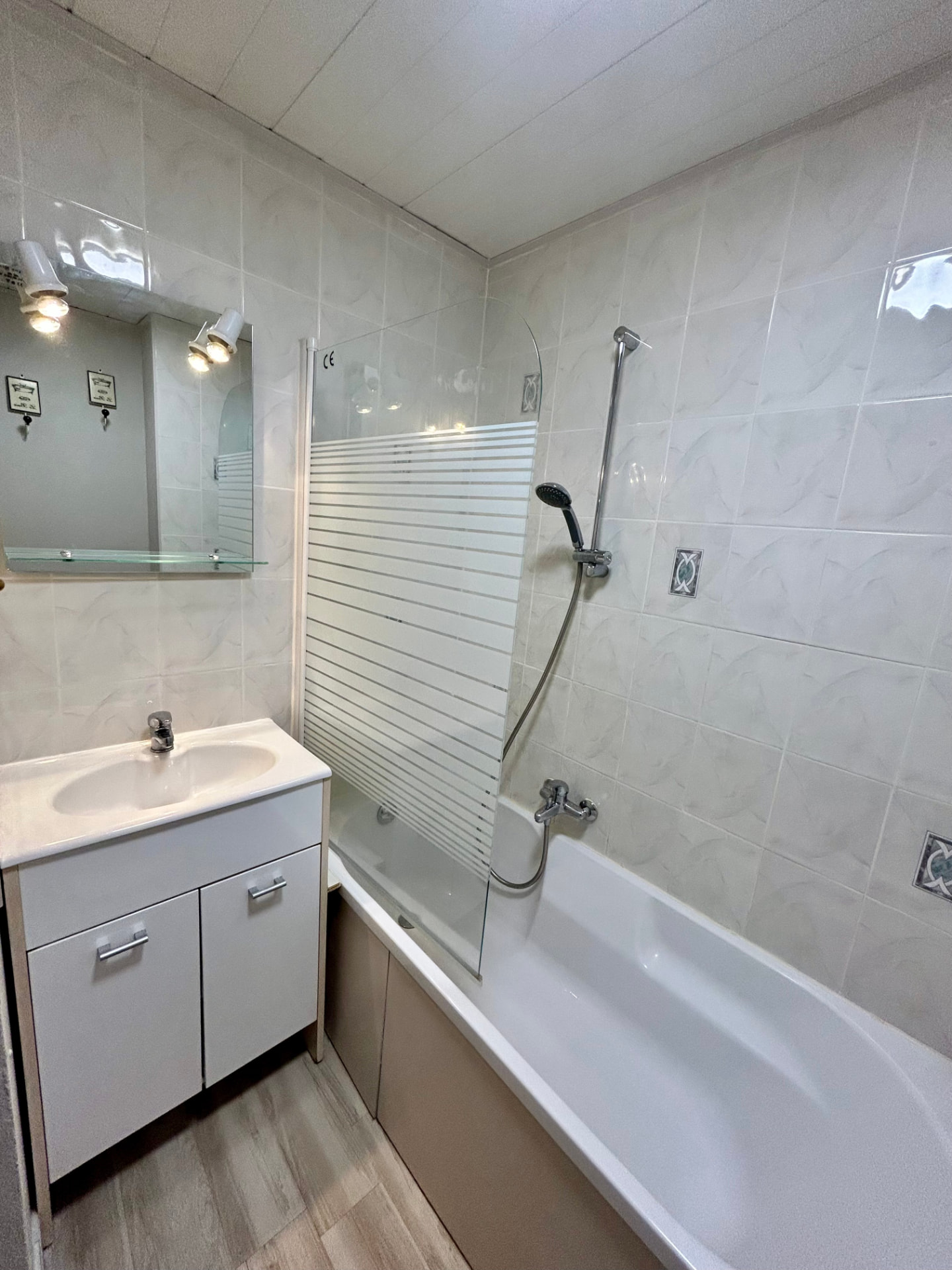 Salle de bain avec baignoire, pare-douche vitré et meuble vasque