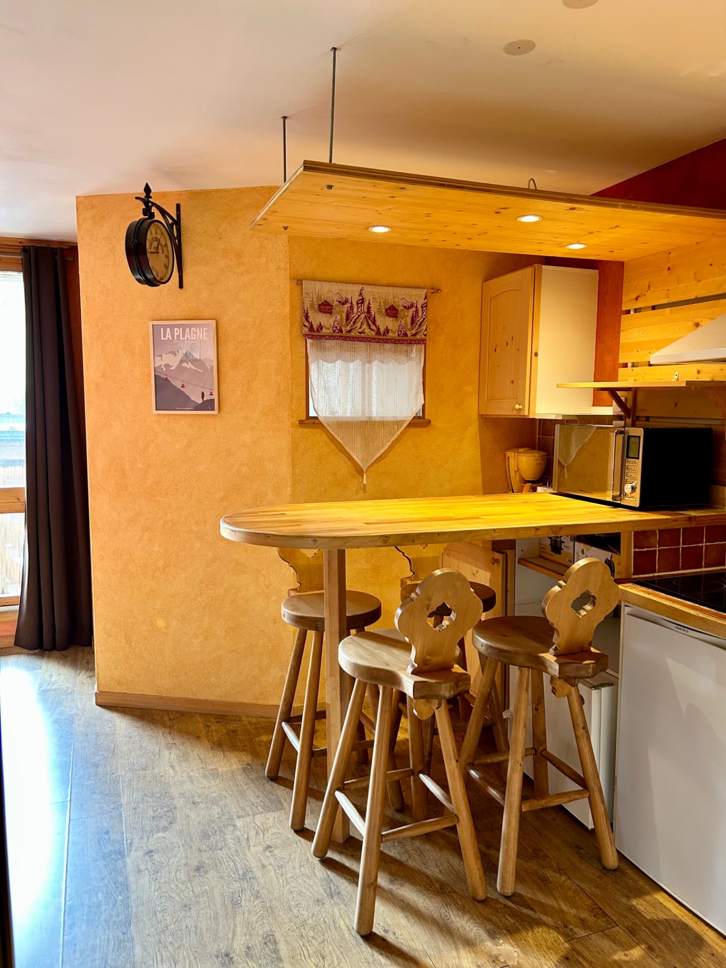 Cuisine équipée avec four micro-ondes, réfrigérateur, hotte et bar à quatre tabourets